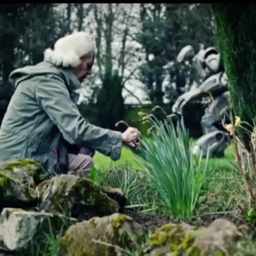 An old women, gardening. Titan the Robot is seen in the background, pushing a lawnmower.