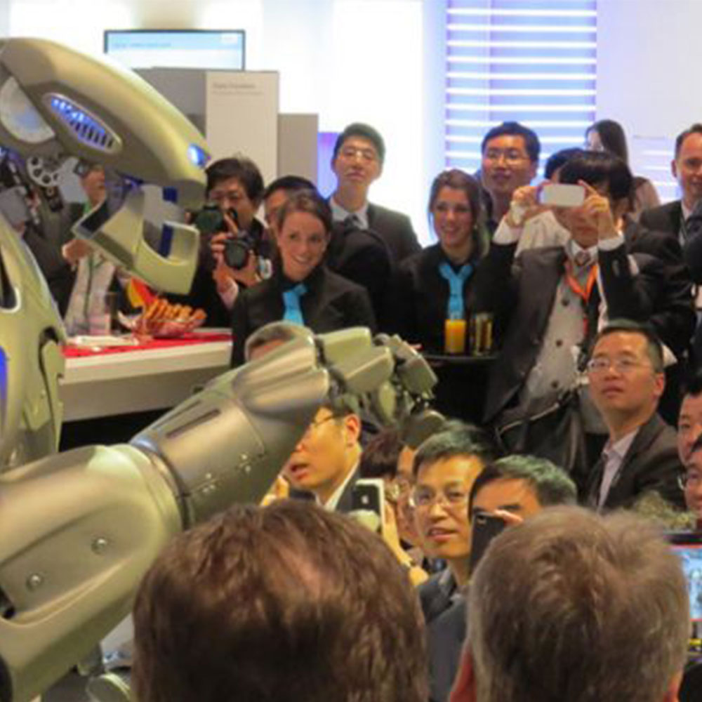 Titan the Robot performs to a crowd, who look in awe, on the Siemens stand, at a trade show