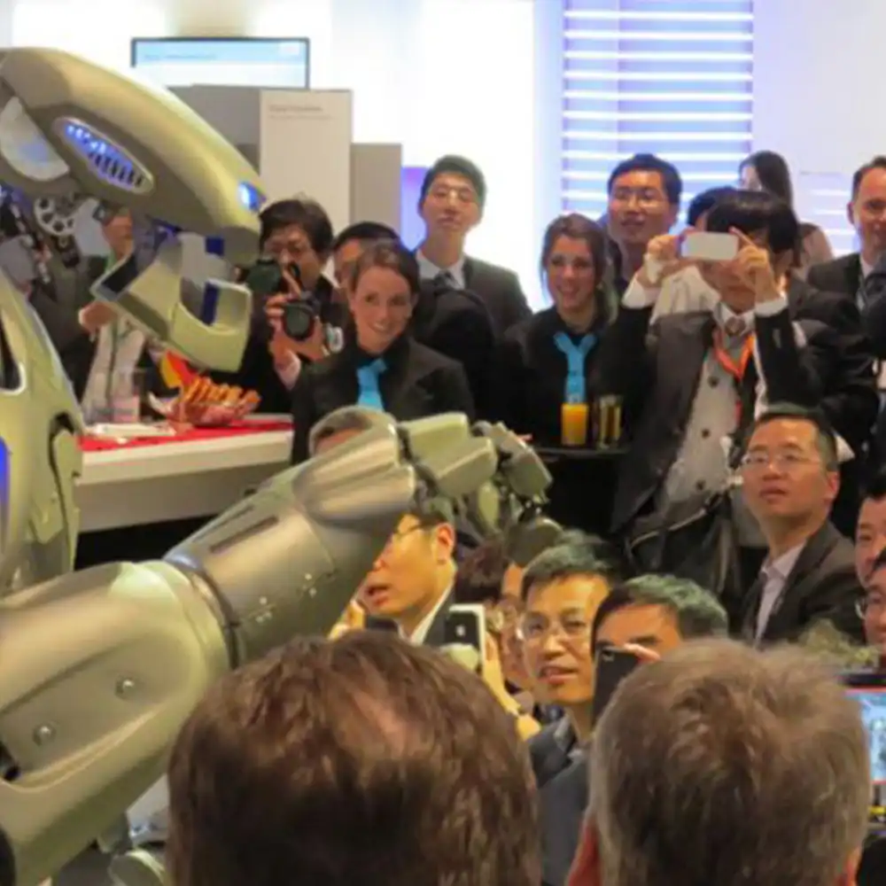 Titan the Robot performs to a crowd, who look in awe, on the Siemens stand, at a trade show