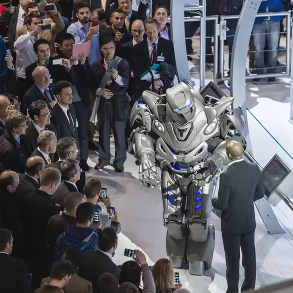Titan the Robot interacts with a presenter on the Siemens stand in close proximity to a large audience who are watching their performance