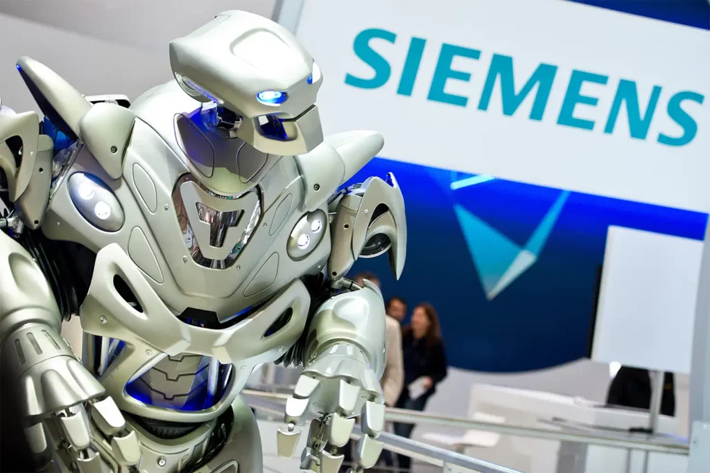 A close up image of Titan the Robot. In the background, a large Siemens logo can be seen as part of their trade show stand.