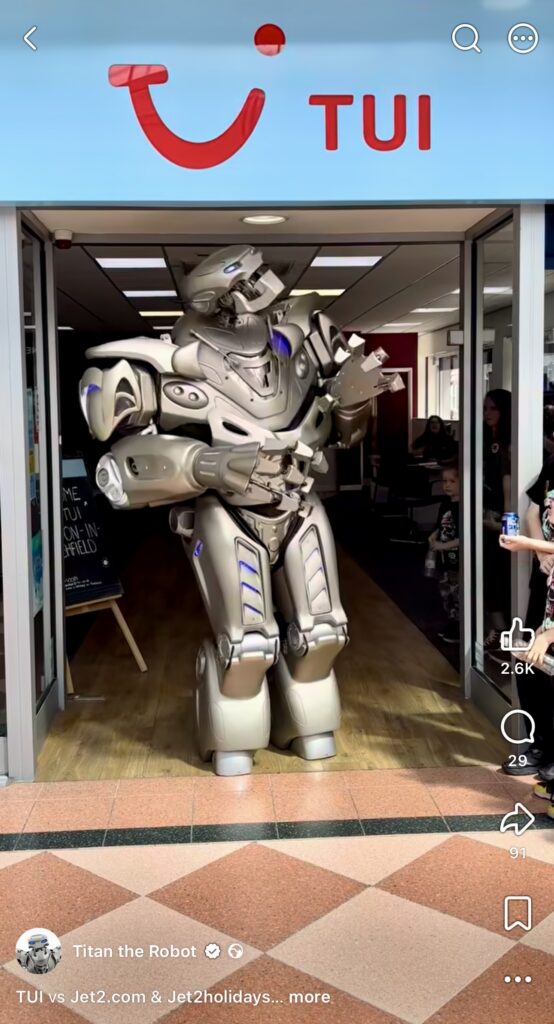 Titan the Robot performs in front of a TUI travel agent store.